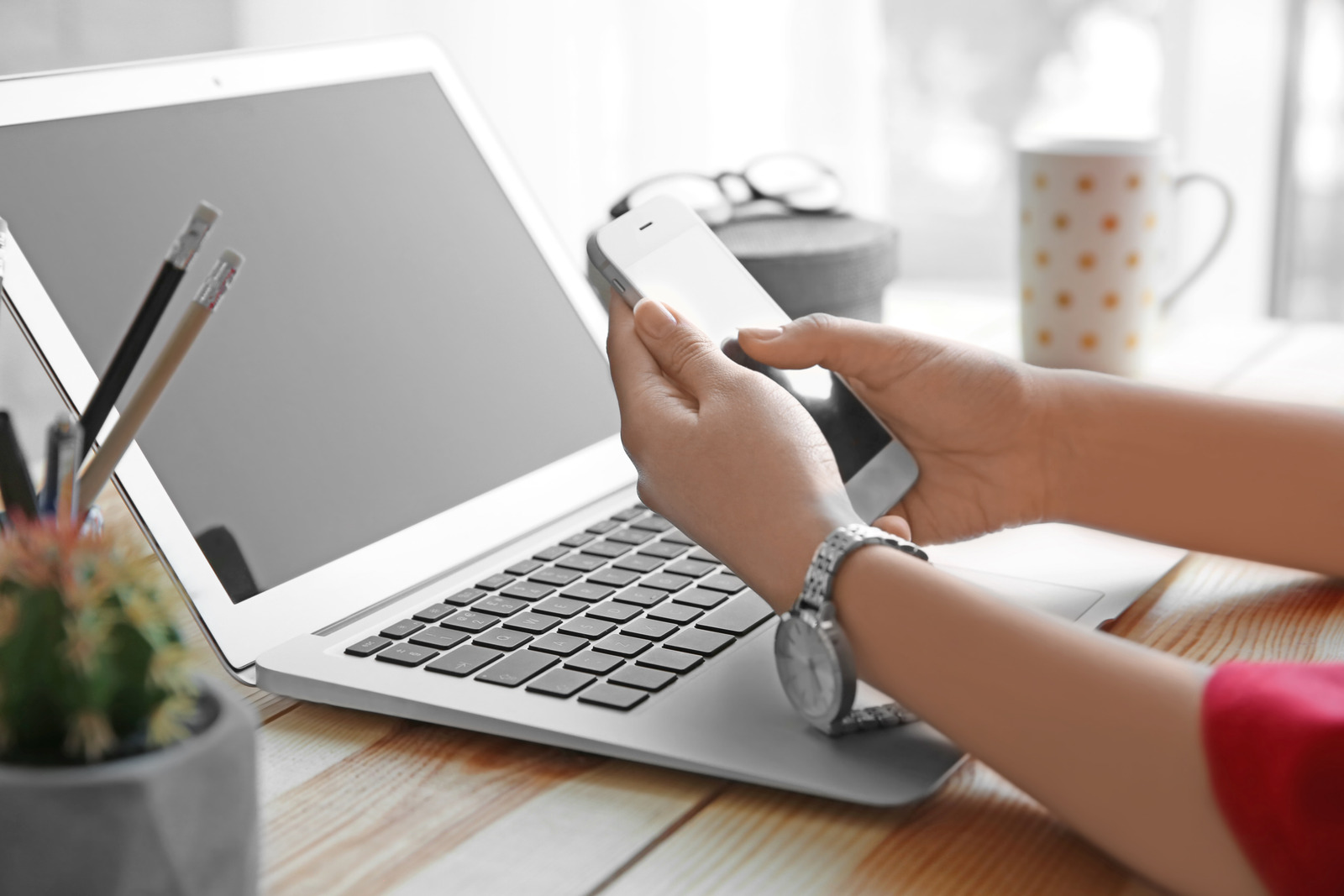 Woman with cell phone and laptop on wooden table